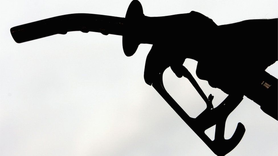 A petrol pump (being held by a motorists hand, in silhouette)