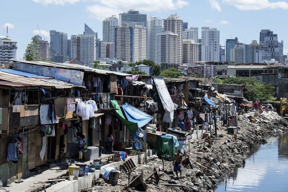 Residents of a Manila slum, pictured in front of the city's financial district