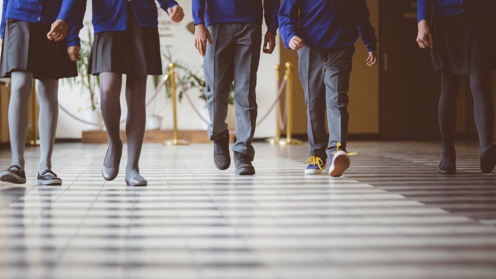 Cropped image of school kids in uniform walking together in a row through corridor