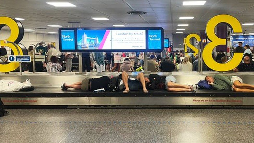 Air passengers wait for their baggage