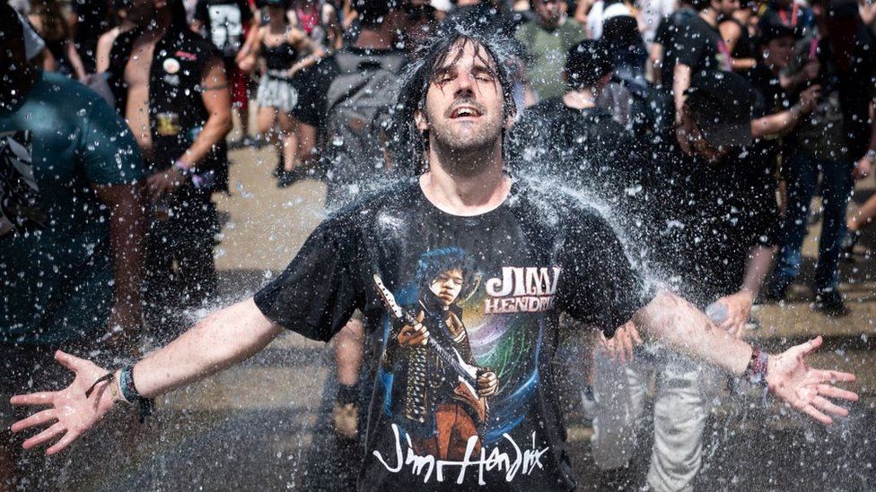 A festival goer cools down with fresh water while taking part in the Hellfest metal music festival on June 17, 2022 in Clisson