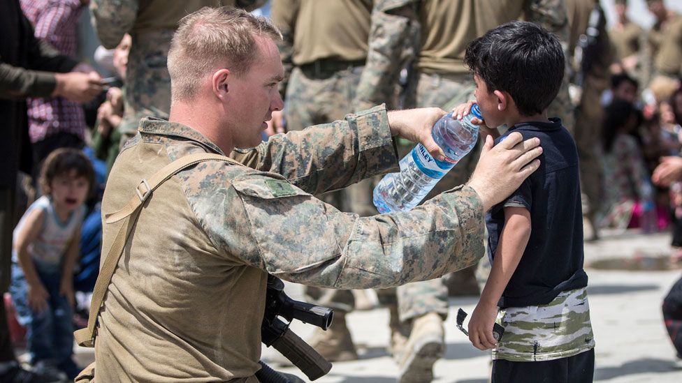 A US Marine provides water to a child during an evacuation at Hamid Karzai International Airport, Kabul, on 20 August 2021