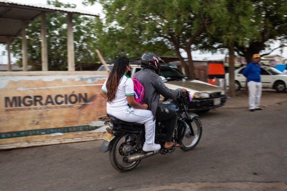 A child crosses the border on the back of a motorcycle