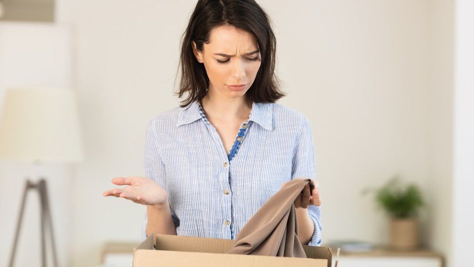 Woman looking confused into box at item