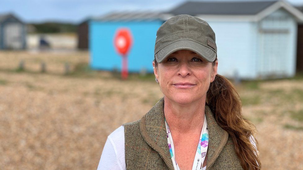 woman in a khaki cap standing in front of beach huts