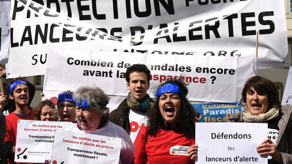 People hold placards reading 'stand up for the whistle-blowers', as they demonstrate outside the courthouse in Luxembourg