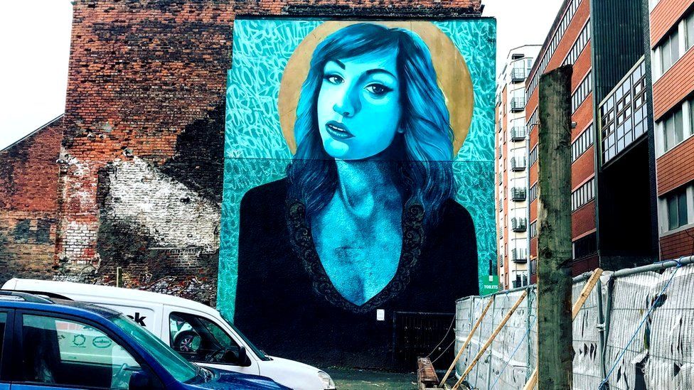 Large portrait of a girl on the side of a car park