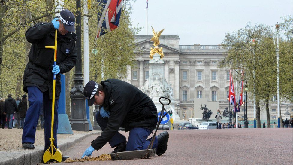 Two police officers carrying out security checks outside Buckingham Palace