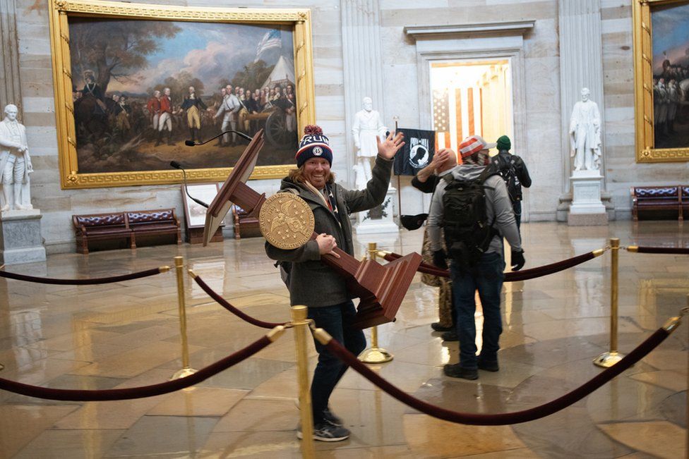 A pro-Trump protester carries the plinth of US Speaker of the House Nancy Pelosi through the Rotunda of the US Capitol Building after a pro-Trump mob stormed the building on 6 January 2021 in Washington, DC.