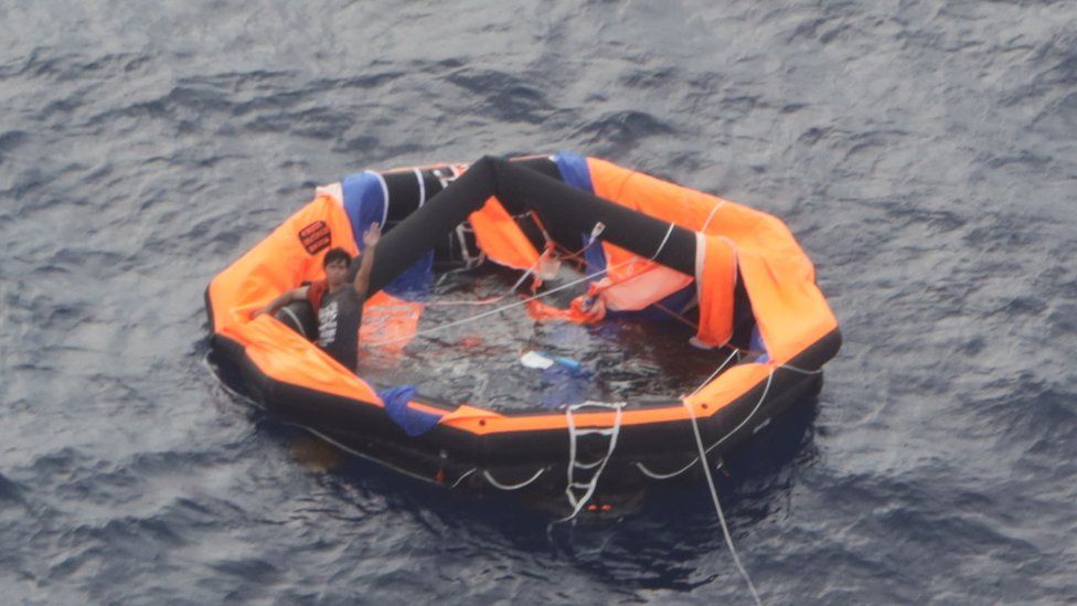A Filipino crew member of the Gulf Livestock 1 waves from a life raft in the East China Sea on 04 September 2020