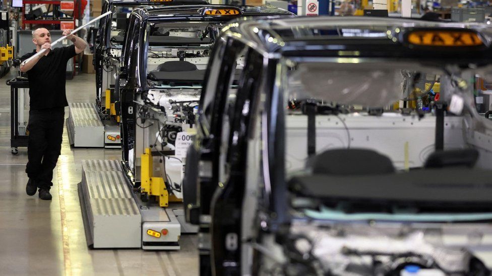 A worker walks along the TX electric taxi production line inside the LEVC (London Electric Vehicle Company) factory in Coventry, Britain,