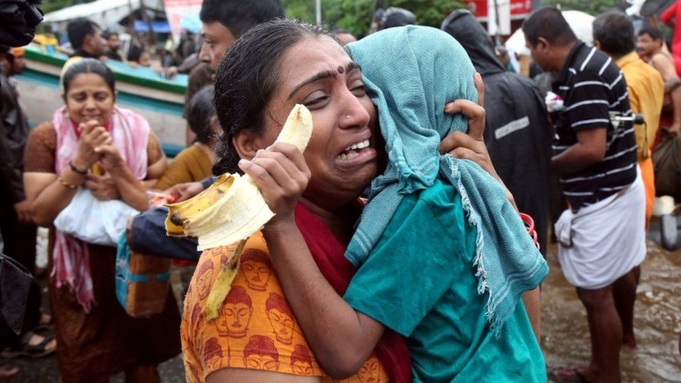 A woman cries as she holds her son after they were evacuated from a flooded area in Aluva, Kerala