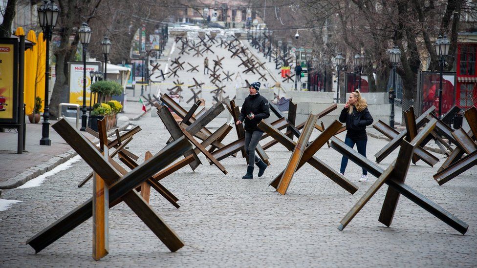 People walk among anti-tank barriers placed to protect historic landmarks in Odesa in March 2022