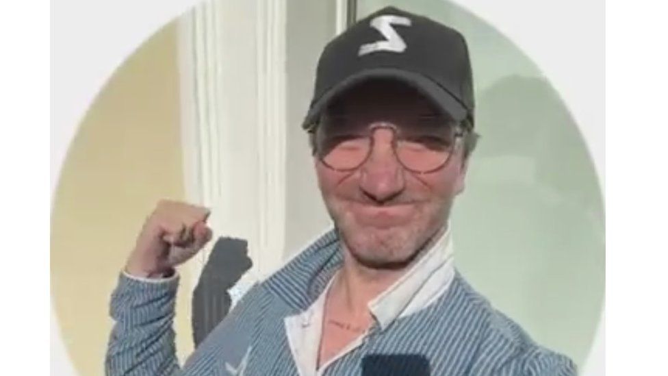 A picture of Anton Krasovsky, a senior employee at RT, punching the air apparently for victory, wearing a cap with a pro-war "Z" symbol