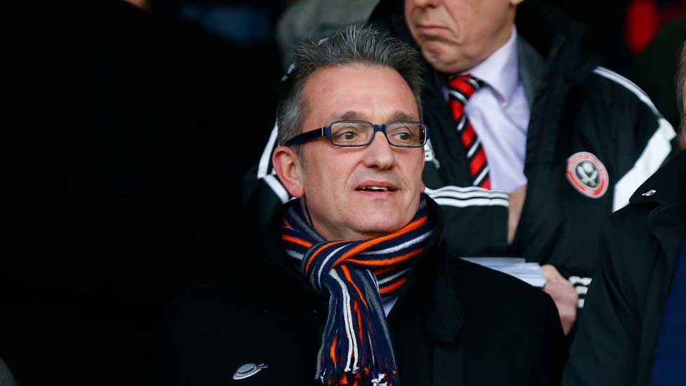 Man with glasses wearing a scarf sitting in a football stand