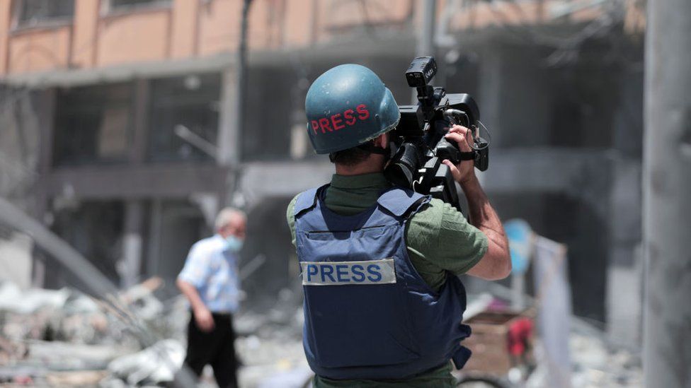 A Palestinian journalist records the rubble of the severely damaged Al-Jawhara Tower in Gaza City on 12 May 2021