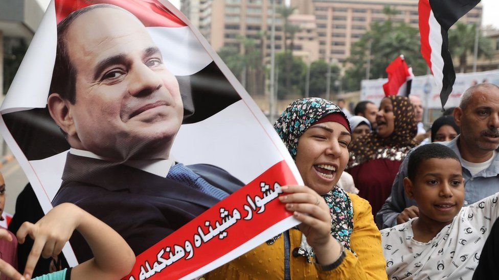 Сторонник президента Египта Абдула Фаттаха ас-Сиси держит плакат, на котором он изображен во время митинга в поддержку его кандидатуры на предстоящих президентских выборах, в Гизе, Египет (2 октября 2023 г.)