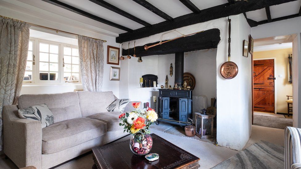 Image of a lounge painted white with beams on the low ceiling and a fireplace.