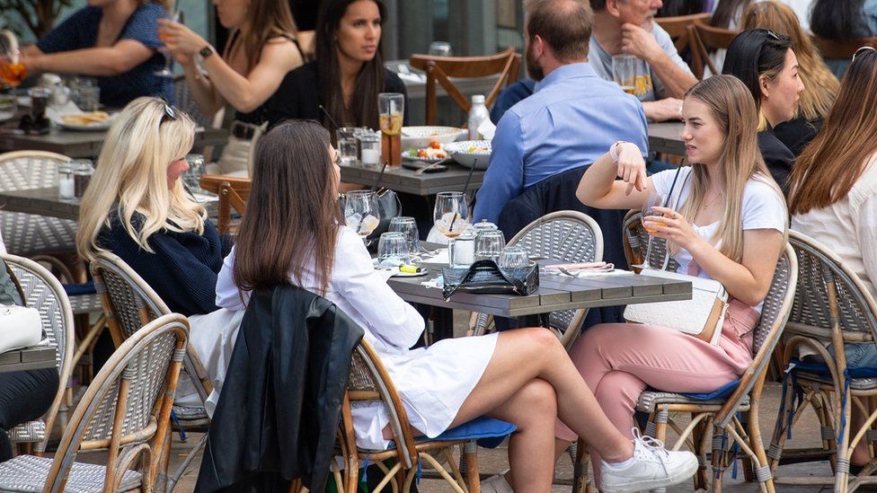 Women eat and drink at outside tables as they enjoy the warm weather on the South Bank in central London