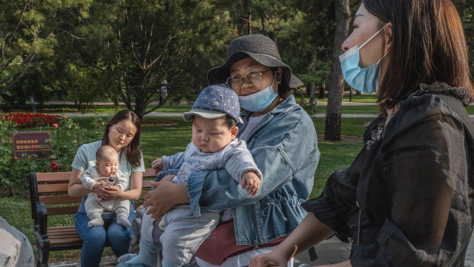 Женщины держат своих младенцев во время разговора в местном парке 12 мая 2021 года в Пекине, Китай.