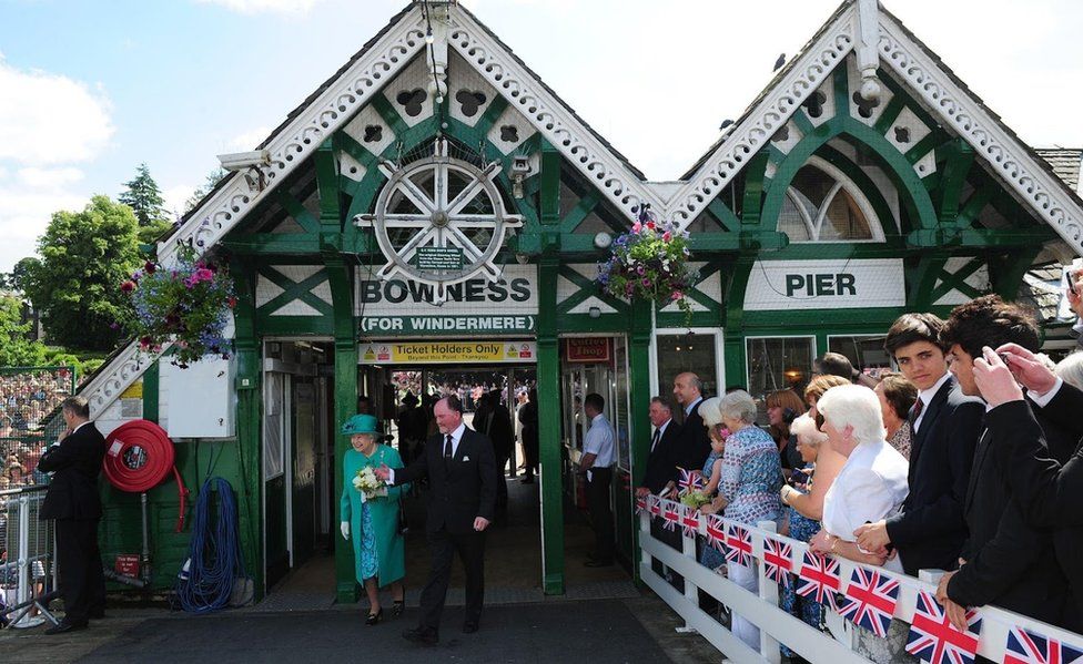 The Queen walks out of the ticket office on to the pier as crowd watches