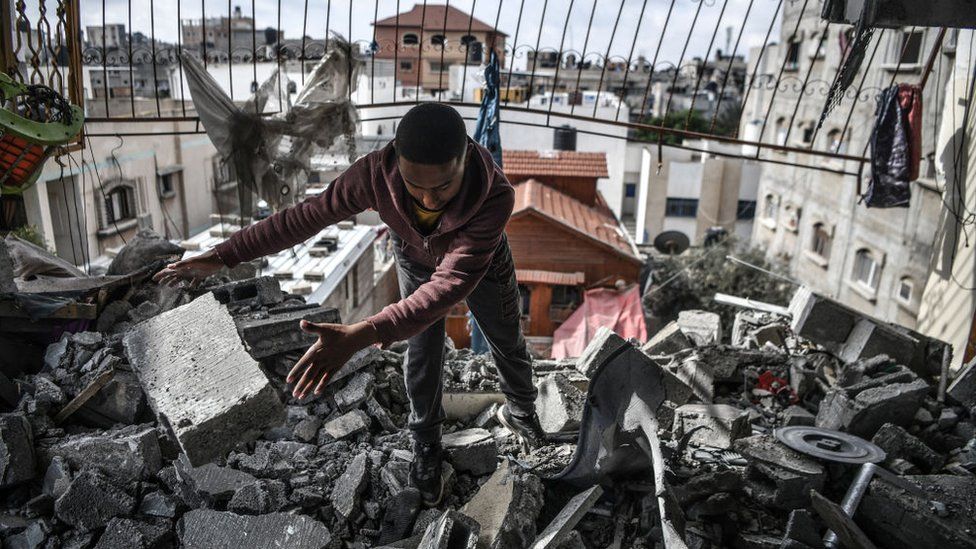 A man in Rafah clears rubble from a building hit by an airstrike