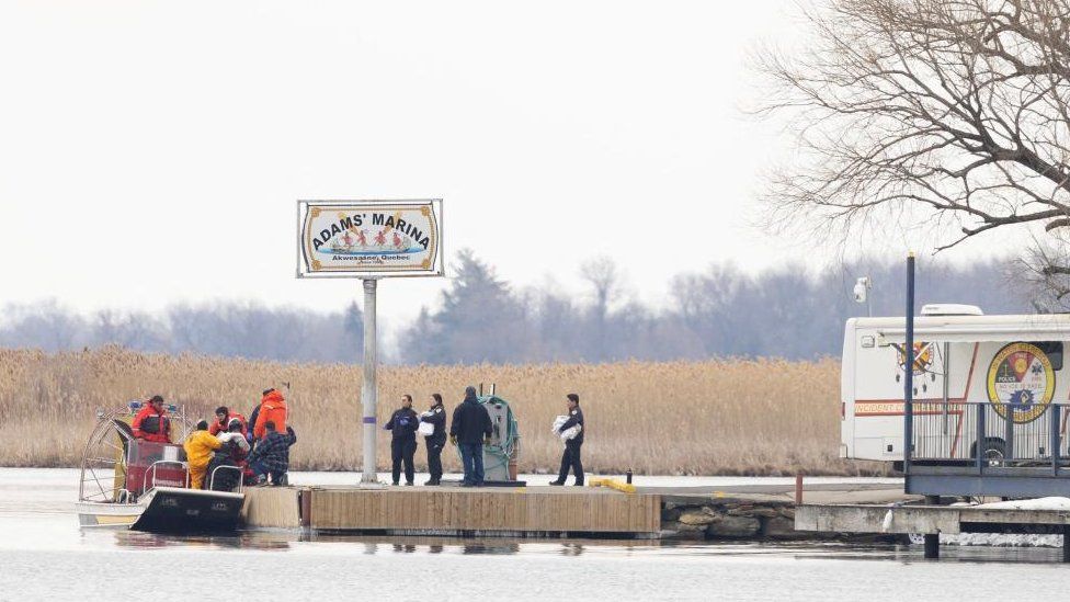 Police and firemen carry a bag off their search boat from the marshland in Akwesasne, Quebec, Canada