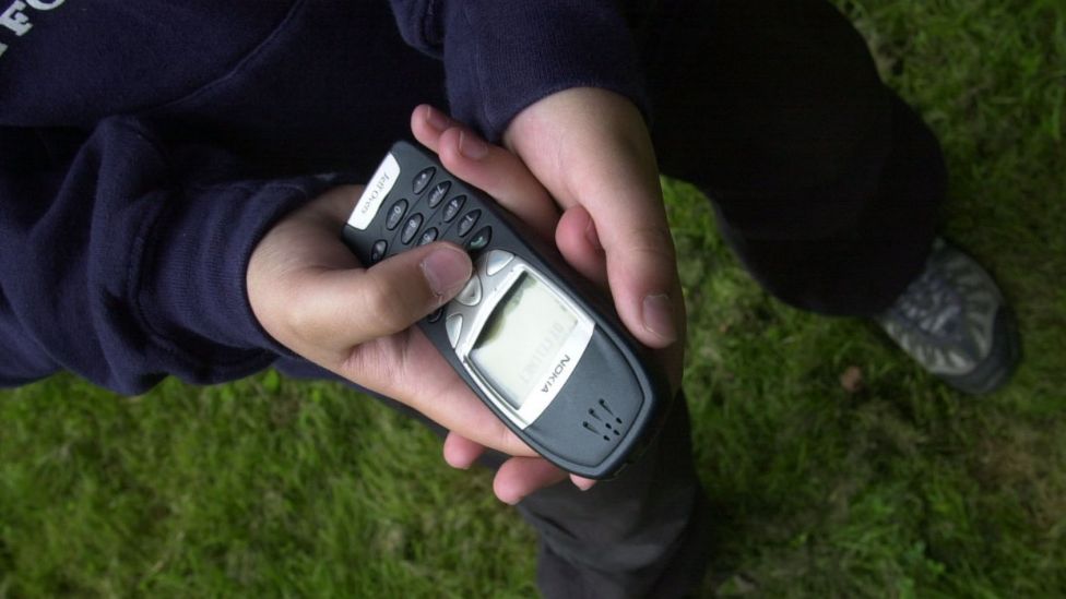 A young boy holding a Nokia phone