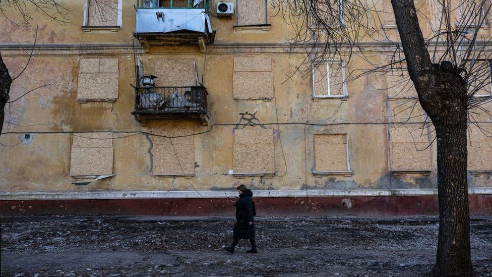 A woman walks by a damaged building in Kramatorsk, eastern Ukraine, on December 19, 2022