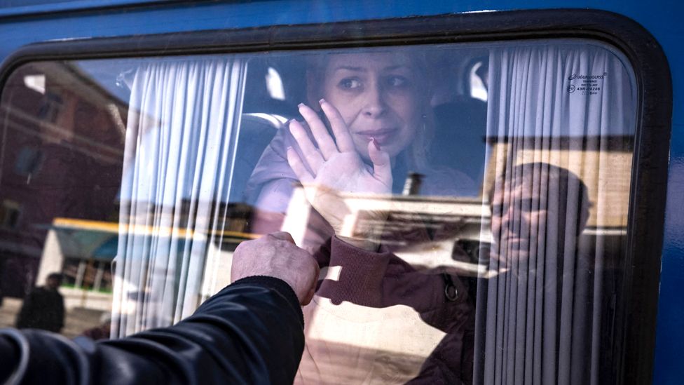 A woman waves to say goodbye to her husband as she leaves on a bus, a day after a rocket attack at a train station in Kramatorsk, on 9 April 2022