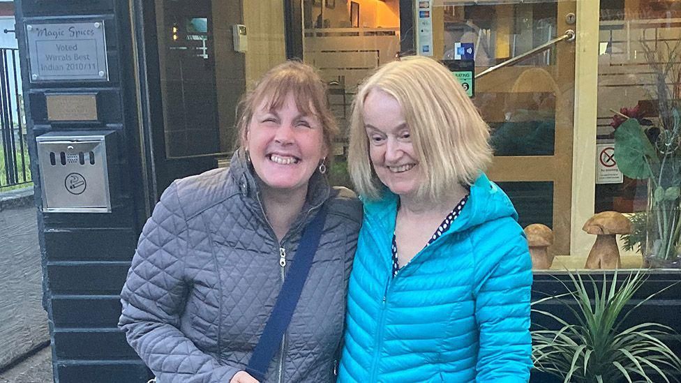 Mandy Redvers-Rowe and Gill Wake standing outside a restaurant with arms round each other smiling