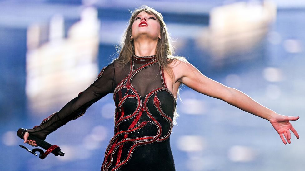 Taylor Swift in a black outfit embroidered with red snakes