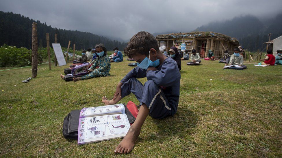 A boy reads a book during a class in the outdoors.