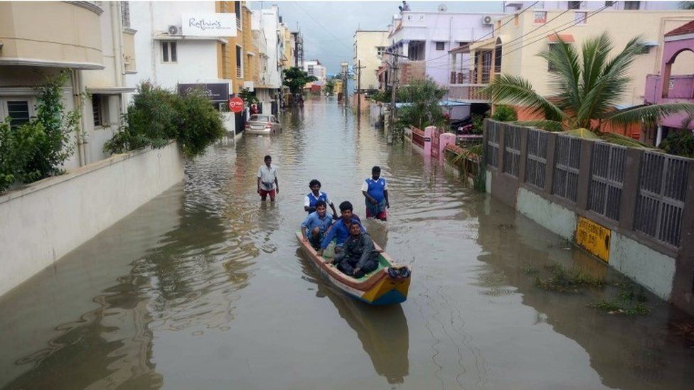 Indian people make their way in a canoe on a flooded street following heavy rain in Chennai on November 16, 2015.