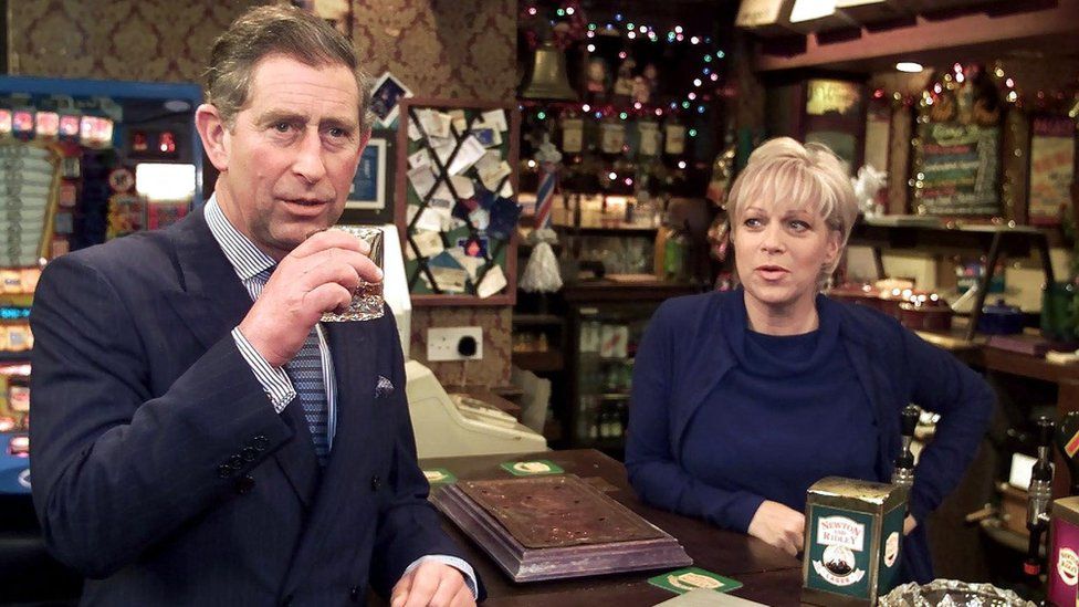 The Prince of Wales (L) enjoys a scotch with 'Coronation Street' landlady Natalie Barnes played by Denise Welch (R) in the Rovers Return pub on the set of the soap Coronation Street 08 December 2000