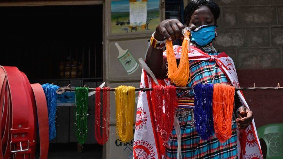 Женщина устанавливает свой стенд, демонстрирующий украшения ручной работы из бисера и кожаные ремни в Талеке в Масаи-Мара, Кения - июнь 2020 г.