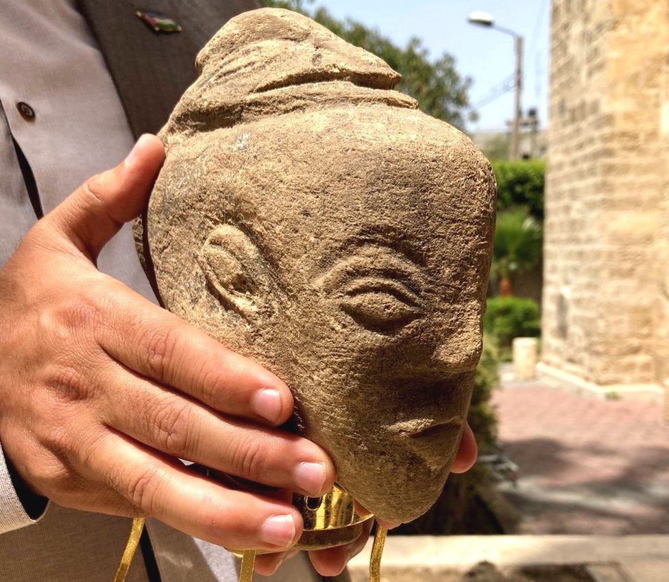 A man holds the limestone head of a 4,500-year-old sculpture said to depict the Canaanite goddess Anat, which was found by a farmer in the Gaza Strip