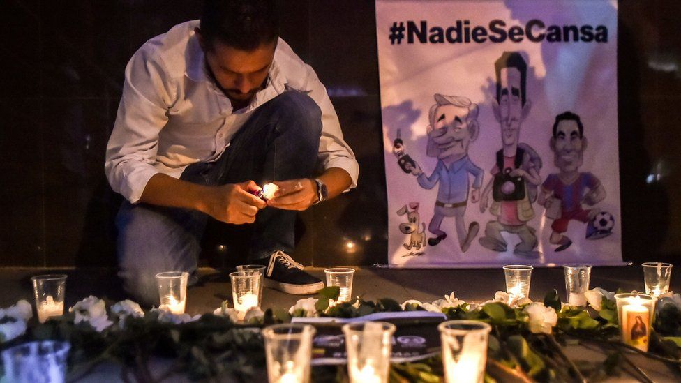 A journalist lights a candle for slain Ecuadorians
