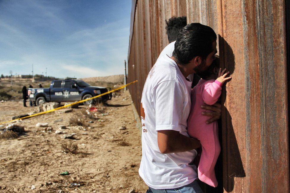 A man holds a baby at the border wall between Mexico and United States, during the "Keep our dream alive" event, in Ciudad Juarez, Chihuahua state, Mexico on 10 December 2017.