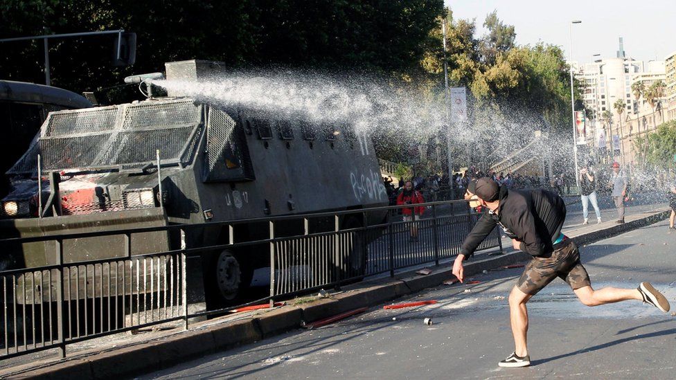 A demonstrator clashes with riot police during a protest against the increase in the subway ticket prices in Santiago