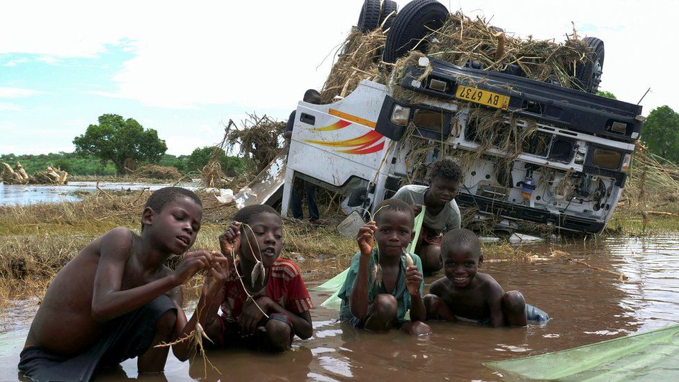 Дети хвастаются своим уловом возле затонувшего корабля, смытого во время тропического шторма Ана на разлившейся реке Шир, устье озера Малави