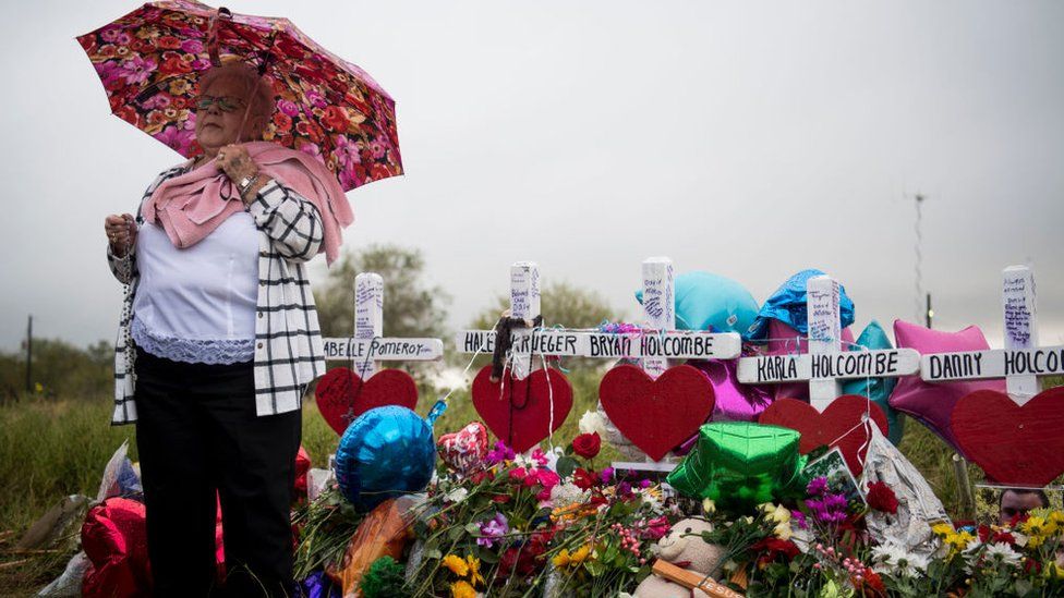 Katy Novak helps to lead dozens of people standing in the rain in prayer and song at the memorial crosses near the Sutherland Springs First Baptist Church one week after 26 people were killed inside in Sutherland Springs, Texas on November 12, 2017