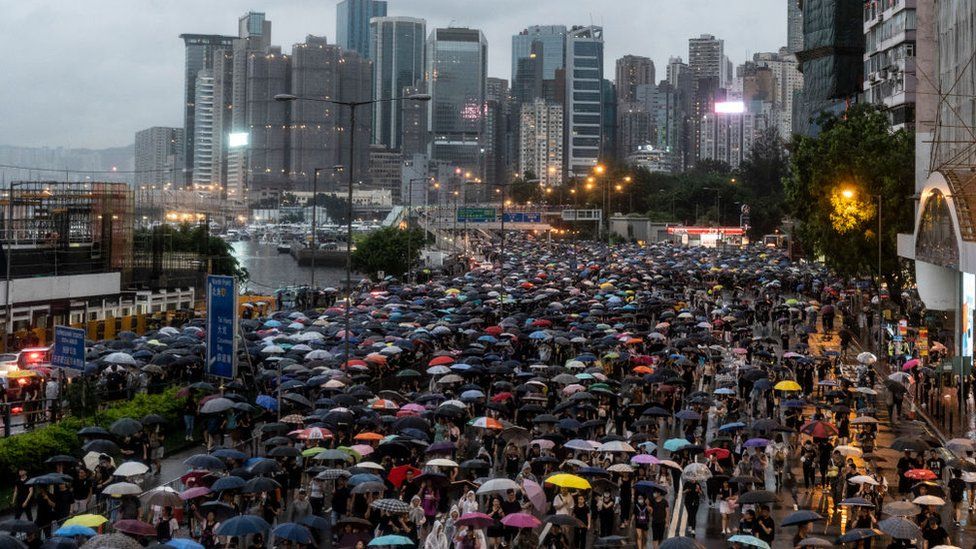 Over a million protesters, carrying umbrellas, march through the streets of Hong Kong with the city's skyscrapers in the background