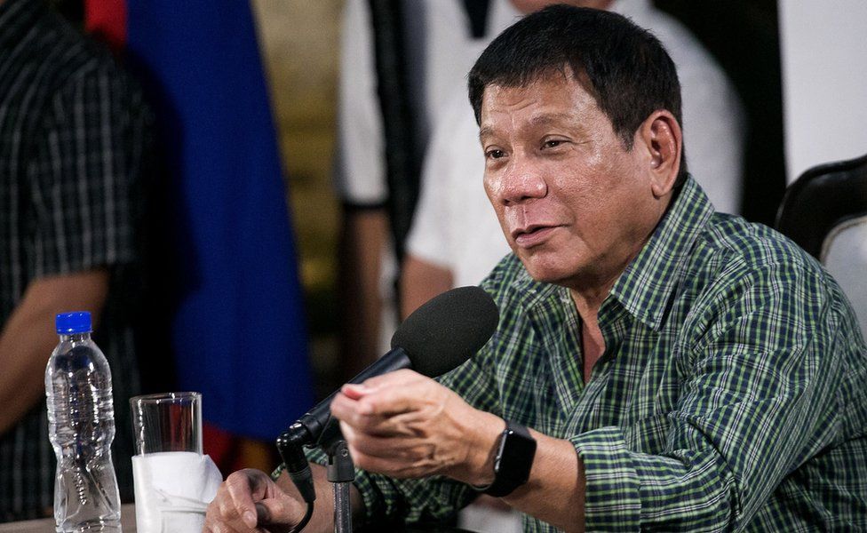 Rodrigo Duterte speaks during his press conference, seated at a microphone and wearing an open-necked check shirt, on 31 May 2016.