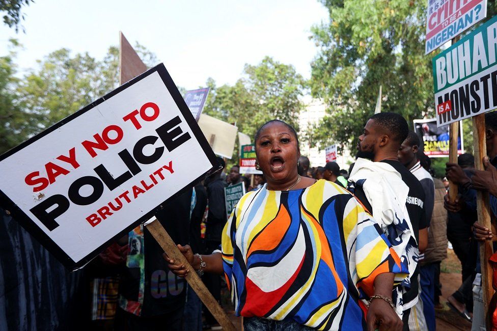 A protestor in Abuja shouts and holds a placard that reads "say no to police brutality".