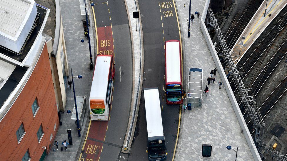 Overhead view of three buses with white roofs driving,