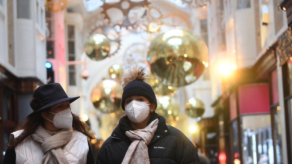 Shoppers pass Christmas decorations on a store in London