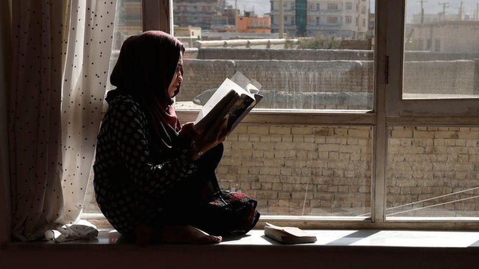 girl reads at her window
