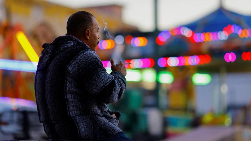 A man smokes in a public plaza in Ciudad Juarez, Mexico, 13 January 2023