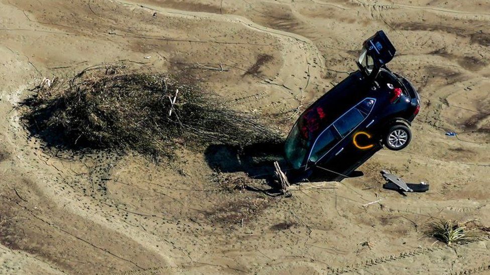 A car is seen stuck in the sand in the aftermath of Cyclone Gabrielle in the Esk Valley near Napier on 18 February, 2023.